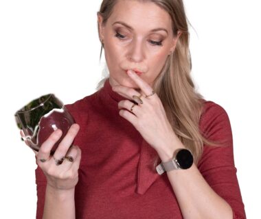 Woman in a red shirt looking at a glass with a collagen supplement inside