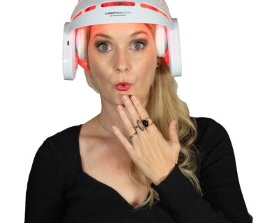 A blonde woman with a shocked expression weraing the Currentbody LED Hair Growth Helmet