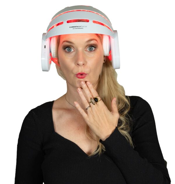 A blonde woman with a shocked expression weraing the Currentbody LED Hair Growth Helmet