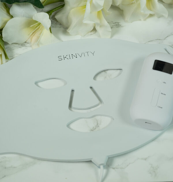 A SKINVITY LED face mask lying on a marble surface